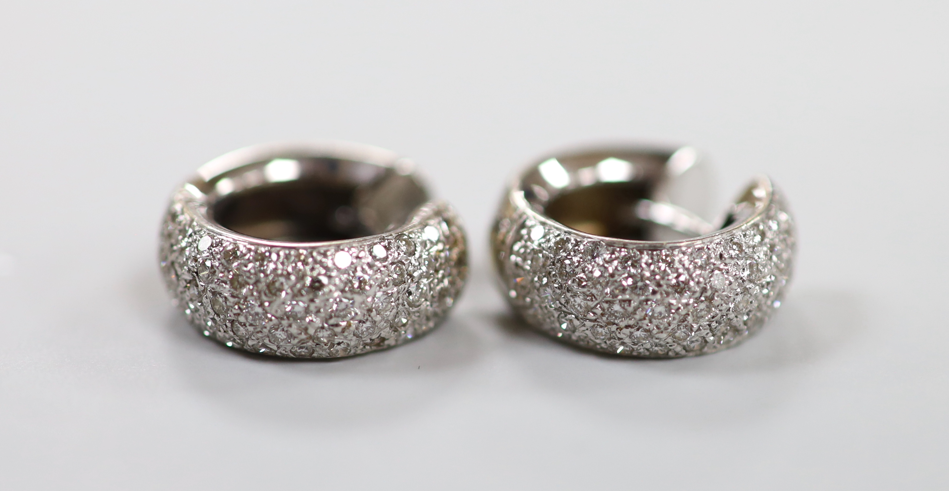 A modern pair of 750 white metal and pave set diamond chip half hoop earrings, 15mm, gross weight 7.4 grams.